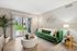 Modern living room with a vibrant green sofa, elegant decor, and natural light from sliding glass doors overlooking a lush garden.