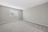 Spacious bedroom with soft carpet flooring and large window for natural light.