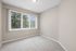 Bright and inviting room with large window and modern vertical blinds, offering a serene view of lush greenery.