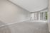 Spacious living room with plush carpeting, featuring large sliding glass doors leading to a serene balcony with greenery views.