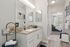 Bright and modern bathroom with sleek vanity, elegant fixtures, and a view into a sunlit bedroom.