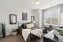 Bright and inviting bedroom with modern decor, featuring a cozy bed, stylish mirrors, and a large window with natural light.