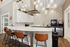 Modern kitchen area featuring a stylish marble countertop, pendant lighting, and leather bar stools, perfect for entertaining.