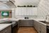 Modern kitchen with elegant marble countertops, sleek cabinetry, and stylish backsplash, featuring a built-in stove and cozy lighting.