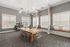Modern meeting room with chic wooden table, transparent chairs, and cozy window seating surrounded by ample natural light.