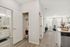 Bright and inviting apartment hallway with sleek hardwood floors, leading to a cozy living room, modern bathroom, and stylish kitchen with stainless steel appliances.