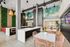 Modern communal dining area with elegant marble countertops, vibrant greenery, stylish wicker chairs, and artistic wall art, creating an inviting and sophisticated atmosphere.