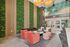 Luxurious lobby space featuring vibrant green walls, elegant seating area with coral and cream chairs, modern decor, and artistic ceiling lights.