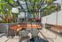 Luxurious outdoor patio with modern pergola, stylish wicker seating, and elegant fireplace surrounded by lush tropical plants.