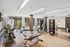 Modern fitness center with state-of-the-art gym equipment, bright lighting, and large windows offering lush outdoor views.