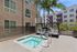 Modern apartment exterior with inviting pool area, surrounded by lush greenery and comfortable lounge chairs under stylish cabanas.