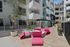 Chic urban patio with vibrant pink lounge chairs and modern planters, perfect for relaxation and entertaining.