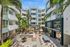 Modern apartment complex featuring lush greenery, stylish outdoor seating, and a billiard table under clear blue skies.