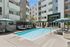 Modern apartment complex featuring a refreshing swimming pool, stylish sun loungers, and chic outdoor seating under elegant umbrellas.