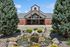 Charming brick building entrance with manicured landscaping and a serene rock water feature, ideal for a welcoming atmosphere.