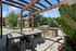 Charming outdoor patio with a pergola, dining table, and built-in grill, perfect for entertaining in a lush garden setting.