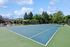 Inviting outdoor tennis court with lush greenery and sunny skies, perfect for sports enthusiasts.
