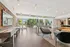 Chic and spacious lounge area featuring a stylish seating arrangement, sleek shuffleboard table, and expansive glass doors opening to a lush garden patio.