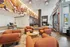 Inviting modern lobby with plush orange seating, artistic ceiling design, and contemporary wall art, perfect for relaxation and entertaining.