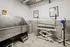 Modern pet grooming area with a sleek stainless steel wash station, adjustable grooming table, and a convenient wall-mount dryer in a bright, tiled room.