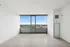 Bright living space with modern flooring and expansive windows offering breathtaking city and lush green views.
