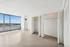Bright, spacious bedroom with floor-to-ceiling windows offering stunning cityscape views and ample closet space.