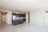 Modern open-concept kitchen and living area with sleek dark cabinetry, stainless steel appliances, and ample natural light.