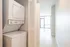 Modern apartment hallway featuring in-unit washer and dryer, leading to bright and airy living space with large windows.