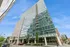 Contemporary high-rise building with sleek glass facade and balconies, set against a vibrant blue sky.