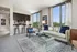 Bright and modern living area with floor-to-ceiling windows, elegant decor, and a stylish open kitchen with bar seating.