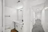 Modern apartment hallway leading to a chic bathroom with sleek fixtures and a large mirror, showcasing contemporary design.