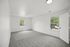 Bright and airy bedroom with plush carpet, large windows, and serene outdoor views perfect for relaxation.