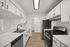 Bright and modern kitchen featuring sleek, white cabinetry, stainless steel appliances, and elegant wood flooring.