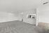 Spacious open-plan living area with plush carpeting and a sleek, modern kitchen featuring stainless steel appliances.
