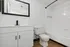 Modern bathroom featuring elegant white cabinetry, a sleek black-framed mirror, and a pristine bathtub with classic tilework.