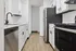 Modern kitchen with sleek stainless-steel appliances, elegant white cabinetry, and stylish wood flooring.