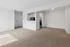 Bright and airy apartment living space with plush carpeting and a stylish kitchen alcove.