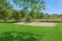 Lush green outdoor space with a sunny sand volleyball court, perfect for recreation and relaxation.