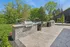 Luxurious outdoor patio with a modern stone grill, overlooking a sparkling pool surrounded by lush greenery, perfect for entertaining and relaxation.