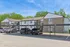 Contemporary apartment building with covered parking surrounded by lush greenery and clear blue skies.