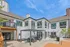 Modern apartment exterior with sleek white siding and large windows, featuring a spacious patio with comfortable seating under a contemporary pergola, perfect for outdoor relaxation.