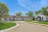 Charming suburban property featuring a picturesque white building with a sloped roof, manicured lawn, and surrounding trees under a bright blue sky.