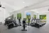 Bright and modern fitness center with multiple treadmills and exercise machines overlooking lush greenery through large windows.