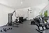 Modern fitness center with state-of-the-art equipment, including exercise bikes, weight machines, and dumbbells, against a backdrop of large windows with a scenic view.