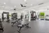 Modern, spacious fitness center with state-of-the-art equipment, including weights, treadmills, and a punching bag, surrounded by bright windows.