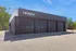 Modern commercial building with sleek black design, three large garage doors, and bold reNEW branding, surrounded by lush greenery.