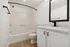 Elegant bathroom with a modern white vanity, chic black fixtures, and warm wood flooring.