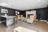 Elegant living space with modern black walls, cozy fireplace, plush seating, and a sleek kitchen island with stylish barstools.