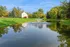 Serene apartment view with lush greenery surrounding a tranquil pond featuring a charming water fountain.