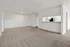 Bright and spacious living area with plush carpeting and an open view into a modern kitchen, offering a cozy and inviting atmosphere.